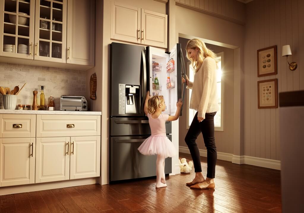 mom and daughter looking inside black stainless steel LG refrigerator
