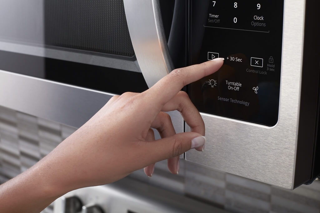 hand touching buttons on Whirlpool Microwave